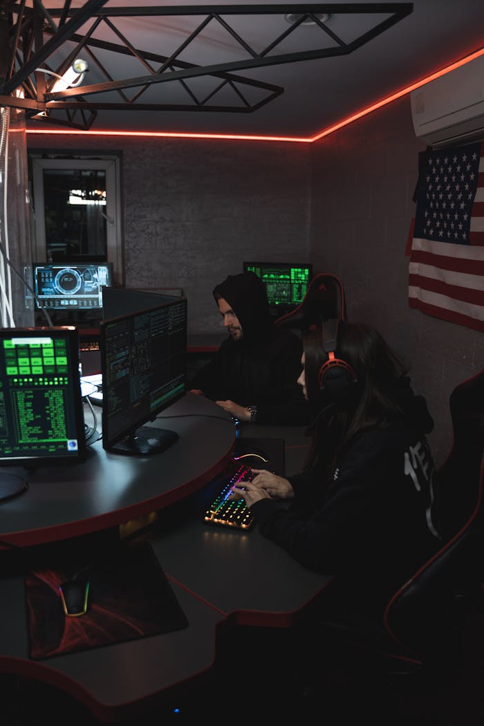 menu-01 Hackers in a dim room working on cyber security systems with multiple screens and digital data.